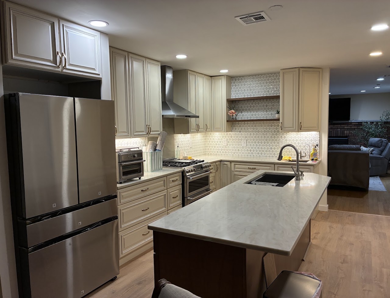 A kitchen with cream shaker cabinets, stone counters and a large island